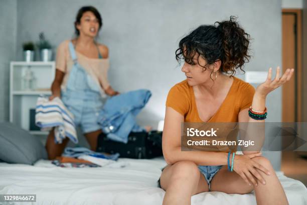 Young Gay Woman Arguing With Her Girlfriend Who Is Packing Her Belongings In Suitcase Stock Photo - Download Image Now