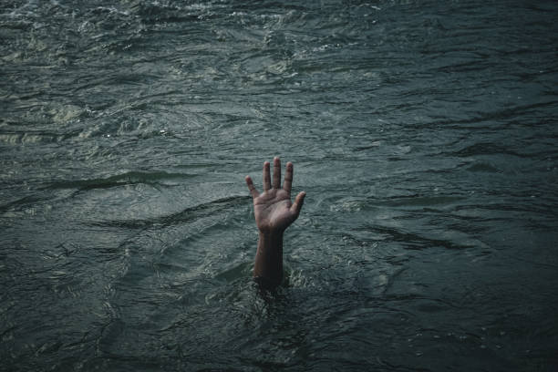 istock Illustration of drowning human hand emerging from the water 1329847128