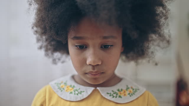 Sad lonely African-american girl with natural black hair looking into camera