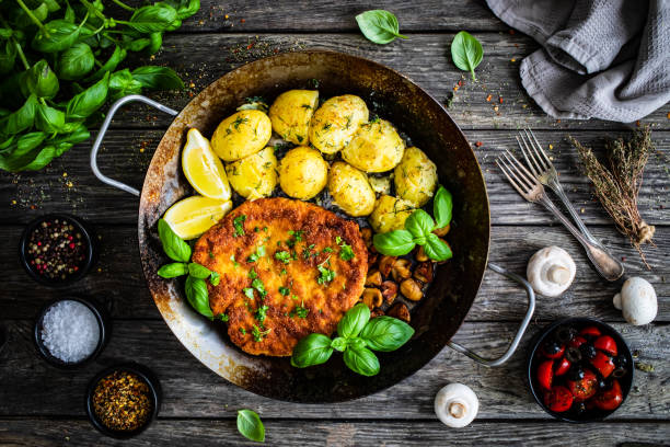 côtelette de porc frite, pommes de terre et champignons blancs dans la poêle à frire - wiener schnitzel photos et images de collection