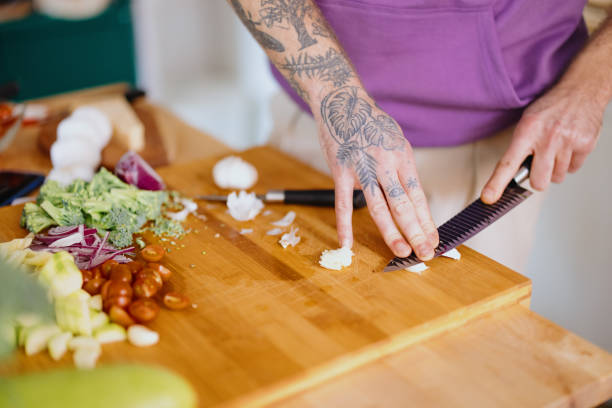 istock Man cuts garlic on a wooden cutting board 1329851040