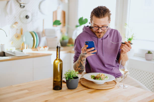 istock The young man eats at kitchen and uses the phone 1329851340