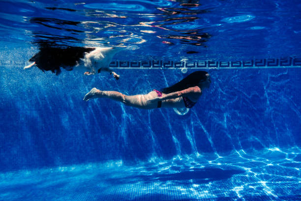 mulher caucasiana e border collie cão nadando na piscina. vista subaquática. horário de verão e conceito de férias - underwater dog adult happiness - fotografias e filmes do acervo