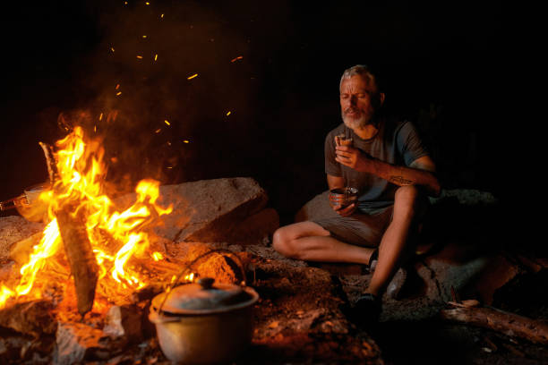 istock Hungry man eating dinner while sitting near campfire in the wild 1329853878