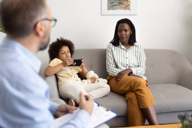 istock Young mother talking with a male psychologist while her phone addicted daughter ignoring them 1329854544