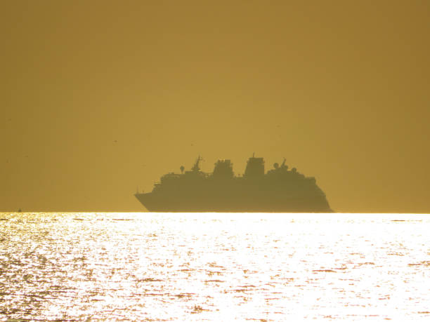istock Cruise ship sailing through the setting sun in silhouette 1329855256