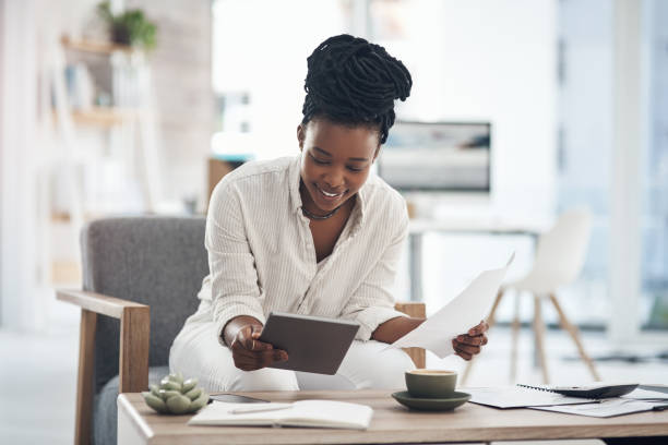 istock Shot of a businesswoman using her digital tablet while reading paperwork 1329859582