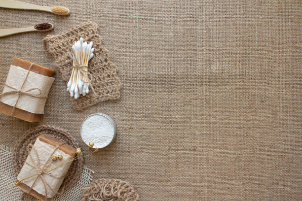 istock Top view on different natural bathroom tools, sustainable lifestyle, zero waste concept. Wooden toothbrushes, bamboo swabs, soap, toothpowder and jute washclothes on fabric background with copy space 1329863552