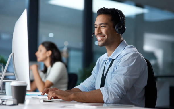 istock Shot of a young man using a headset and computer in a modern office 1329866232