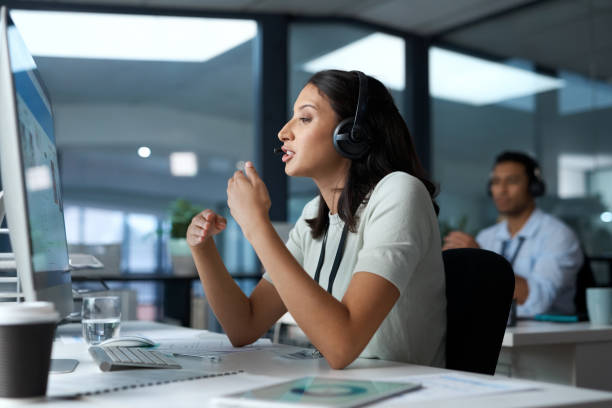 istock Shot of a young woman using a headset and computer in a modern office 1329866247