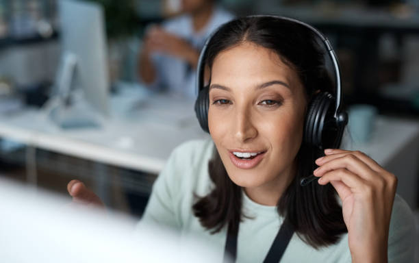 istock Shot of a young woman using a headset and computer in a modern office 1329866260