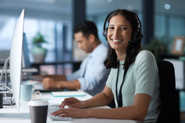 istock Portrait of a young woman using a headset and computer in a modern office 1329866355