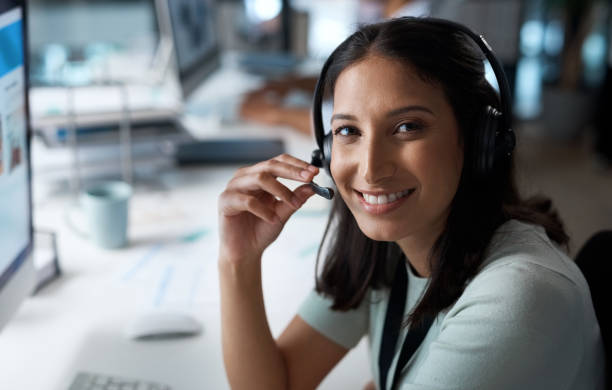 istock Portrait of a young woman using a headset and computer in a modern office 1329866368