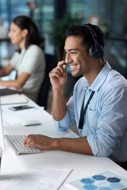 istock Shot of a young man using a headset and computer in a modern office 1329866400