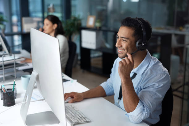 istock Shot of a young man using a headset and computer in a modern office 1329866403