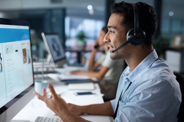 istock Shot of a young man using a headset and computer in a modern office 1329866405