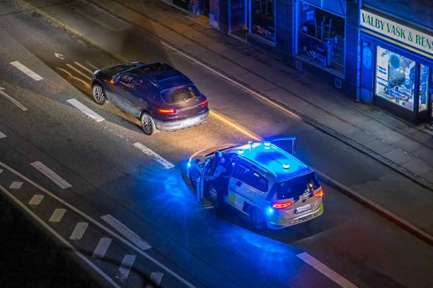 Two police men getting outside their car during work doing traffic control in the middle of the night