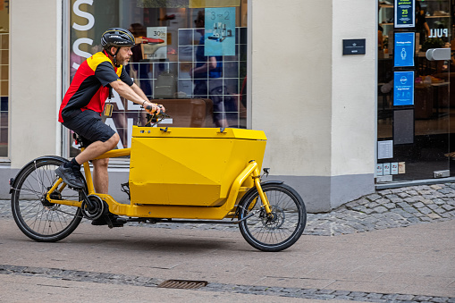 Parcel delivery service man from the company DHL at a professional cargo bike in the center of Copenhagen