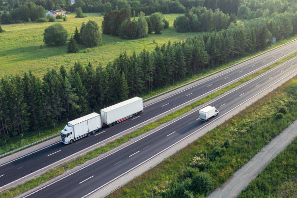 Transportation on the highway A truck with trailer and a delivery truck travelling in opposite directions on a highway in summer. drone point of view road stock pictures, royalty-free photos & images