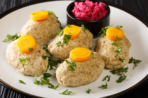 Gefilte Fish Boiled fishballs served with horseradish and carrots close-up in a plate on the table. horizontal