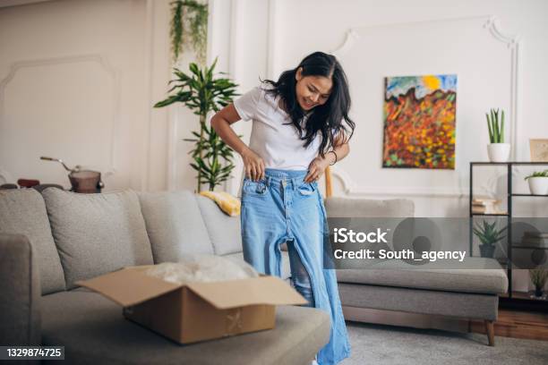 Woman Received A Package At Home Stock Photo - Download Image Now - Trying On, Women, Jeans