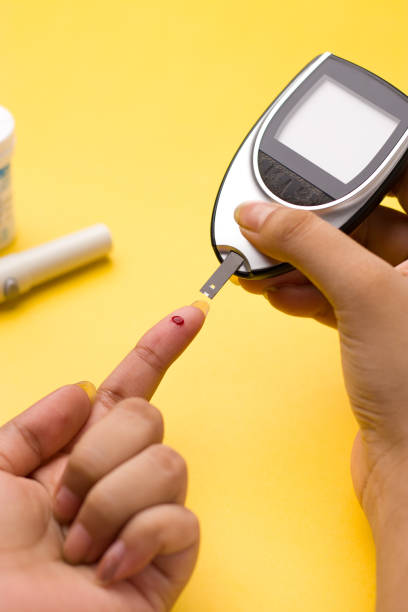 medidor de glucosa en sangre, el valor de azúcar en la sangre se mide en un dedo sobre fondo amarillo. - diabetes hypoglycemia insulin medical exam fotografías e imágenes de stock