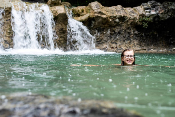 istock Woman swimming in the mountain river with a waterfall 1329878080