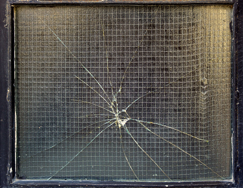 shattered and cracked glass after hitting a metal framed window - lines of bandalism