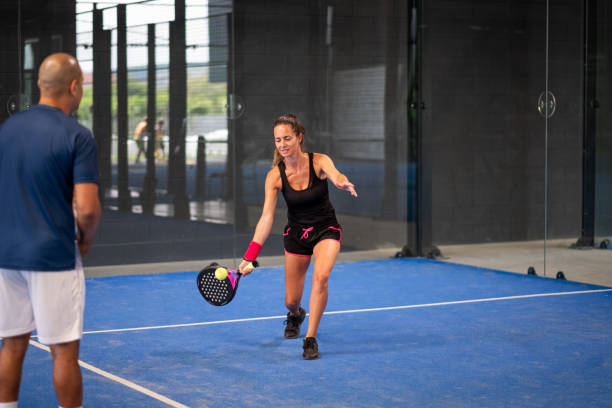 monitor de enseñanza de la clase de pádel a la mujer, su estudiante - entrenador enseña a la niña a jugar al pádel en la pista de tenis cubierta - racketball racket ball court fotografías e imágenes de stock