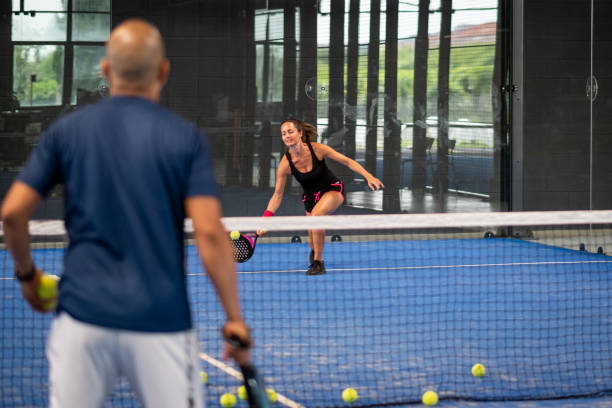 monitor de enseñanza de la clase de pádel a la mujer, su estudiante - entrenador enseña a la niña a jugar al pádel en la pista de tenis cubierta - tennis in a row team ball fotografías e imágenes de stock