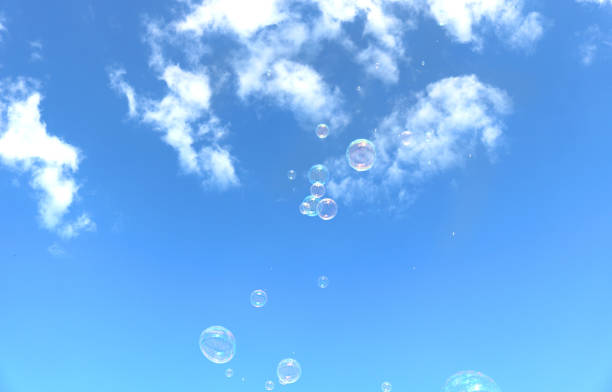 several soap bubbles group in the blue sky with white clouds in the background