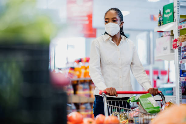 Woman shopping in supermarket wearing coronavirus face mask. Woman shopping in supermarket wearing coronavirus face mask. kn95 face mask photos stock pictures, royalty-free photos & images