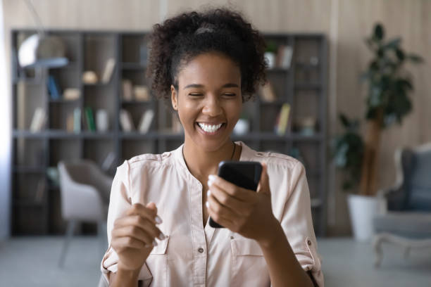 Close up African American woman laughing, looking at phone screen