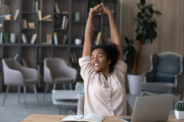 heureuse femme afro-américaine insouciante tendue les mains sur le lieu de travail - facilité photos et images de collection