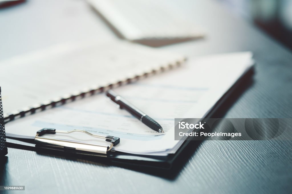 Shot of a notebook and pen on a desk in an office Organisation is essential to productivity Document Stock Photo