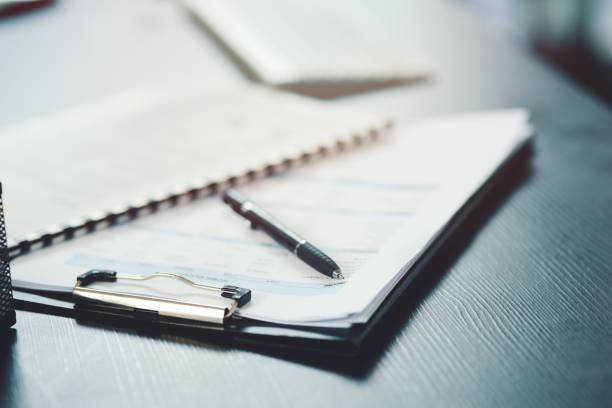 shot of a notebook and pen on a desk in an office - evrak işleri stok fotoğraflar ve resimler