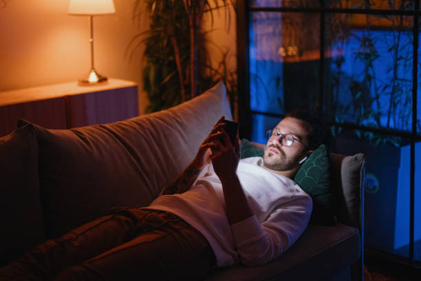 istock Man texting on mobile phone while relaxing at home late at night 1329882657