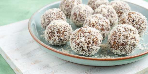 Home made energy protein balls with coconut flakes and nut butter, banner Home made vegan energy protein balls with coconut flakes, almond butter, oats, nuts, dates, dried fruit, flax and hemp seeds served on white wooden board. oats food stock pictures, royalty-free photos & images