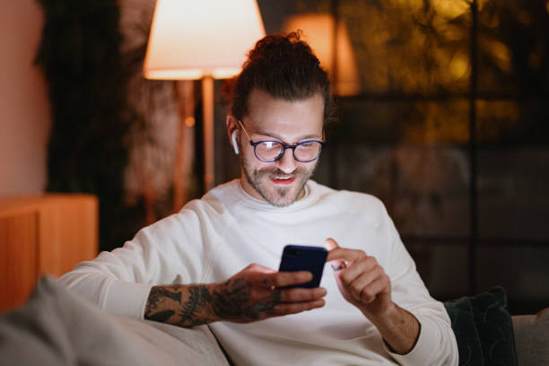 istock Man texting on mobile phone while relaxing at home late at night 1329882794