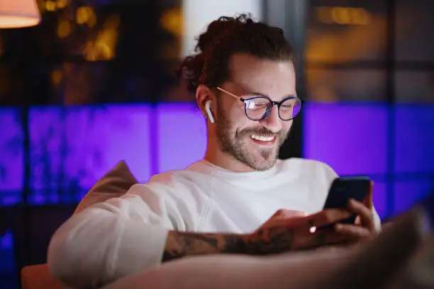 Man looking at smart phone late at night using internet dating app