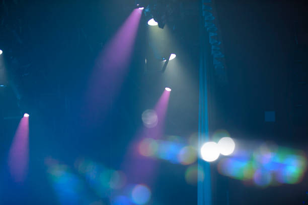 Blue concert background with pink rays and bokeh spots.
