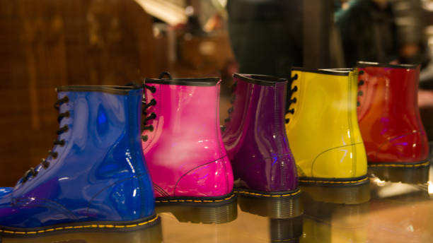 Five shining boots in a row in a storefront. Same model, five different colours: blue, pink, lila, yellow and red. London, UK