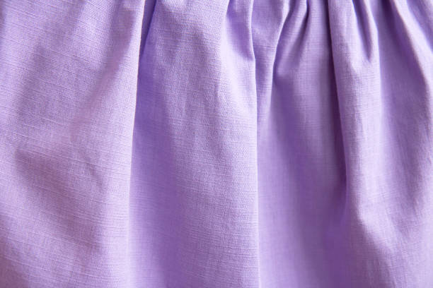 Beautiful nude violet fabric texture with folds and contrasting shadows . Draped background of purple cotton, texture. Copy space. Close up