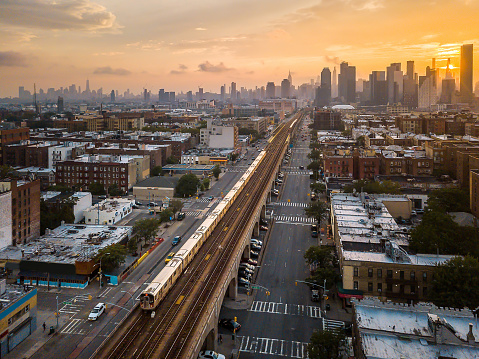 Subway train going trough Sunnyside Queens during sunset on a cloudy summer day. New York aerial skyline in the United States of America