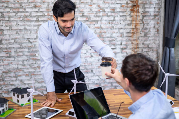 istock Engineer clinking coffee cup in office to congratulate wind power planning success in office. 1329893011