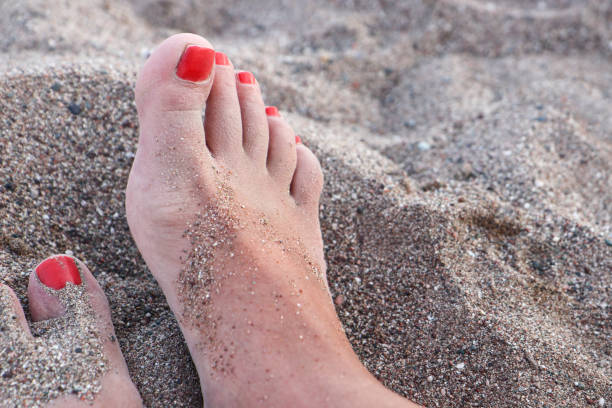 istock Woman's Feet With Red Nails Covered With Sand 1329894349