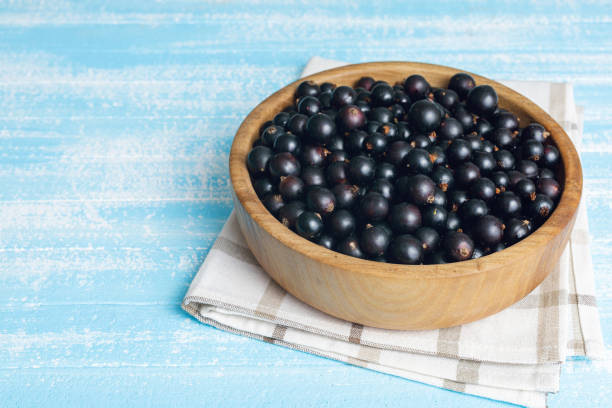 istock Fresh black currant in wooden bowl on dark table 1329894845