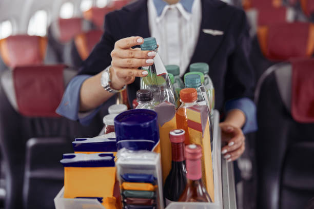 Stewardess take water bottle from trolley cart Stewardess take water bottle from trolley cart in passenger cabin of airplane jet. Modern plane interior. Cropped image of woman wear uniform. Civil commercial aviation. Air travel concept cabin crew stock pictures, royalty-free photos & images