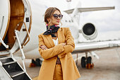Businesswoman with crossed arms near airplane jet