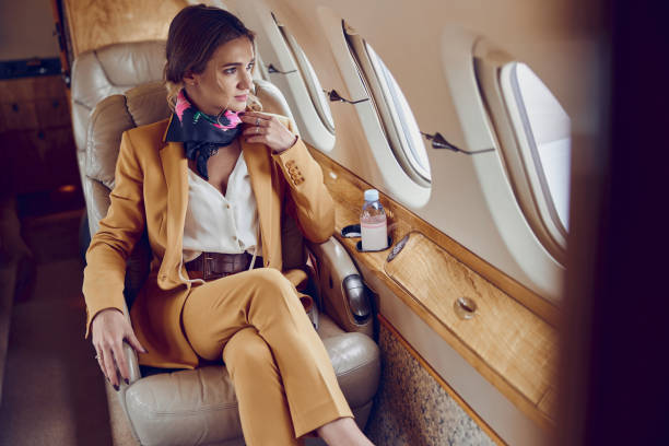 Business woman looking from window in airplane Businesswoman looking from window in private airplane jet. Modern passenger plane. Young european woman wear formal suit. Civil commercial aviation. Concept of air travel and business passenger cabin photos stock pictures, royalty-free photos & images